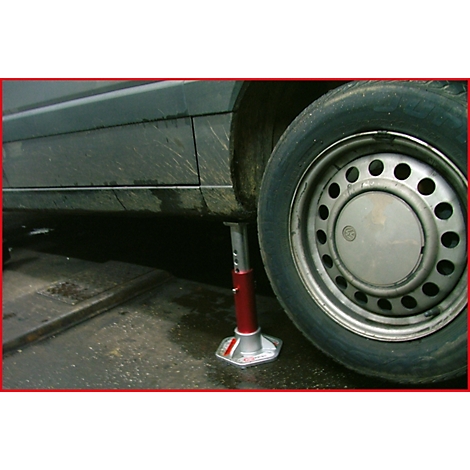 Ein Auto wird mit einem roten Wagenheber angehoben, um einen Reifen zu wechseln.